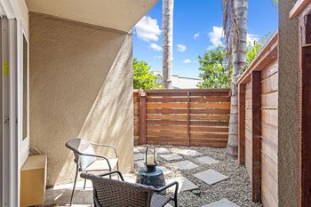 A patio with two chairs and a fire hydrant in front of a wooden fence